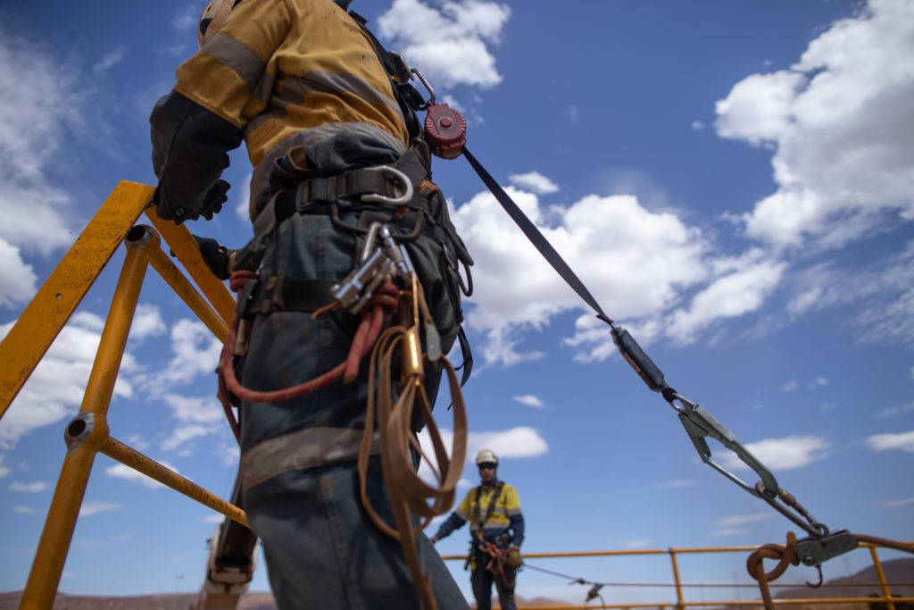 Workers using fall protection equipment while performing elevated construction work on a job site.