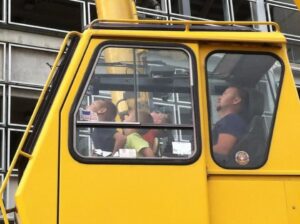 Wayne Essman in the cab of a mobile crane sharing the operator's view with children during a community event.